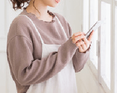 スマートフォンで連絡をする女性のイメージの写真